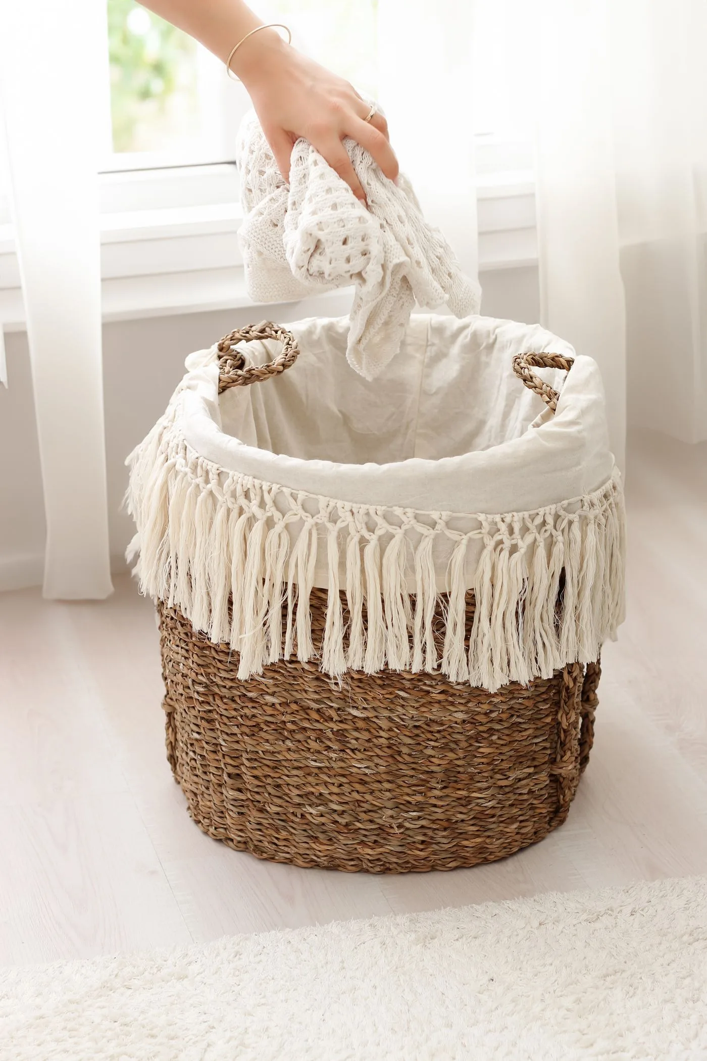 A cloth-lined woven basket with a hand placing a textile inside