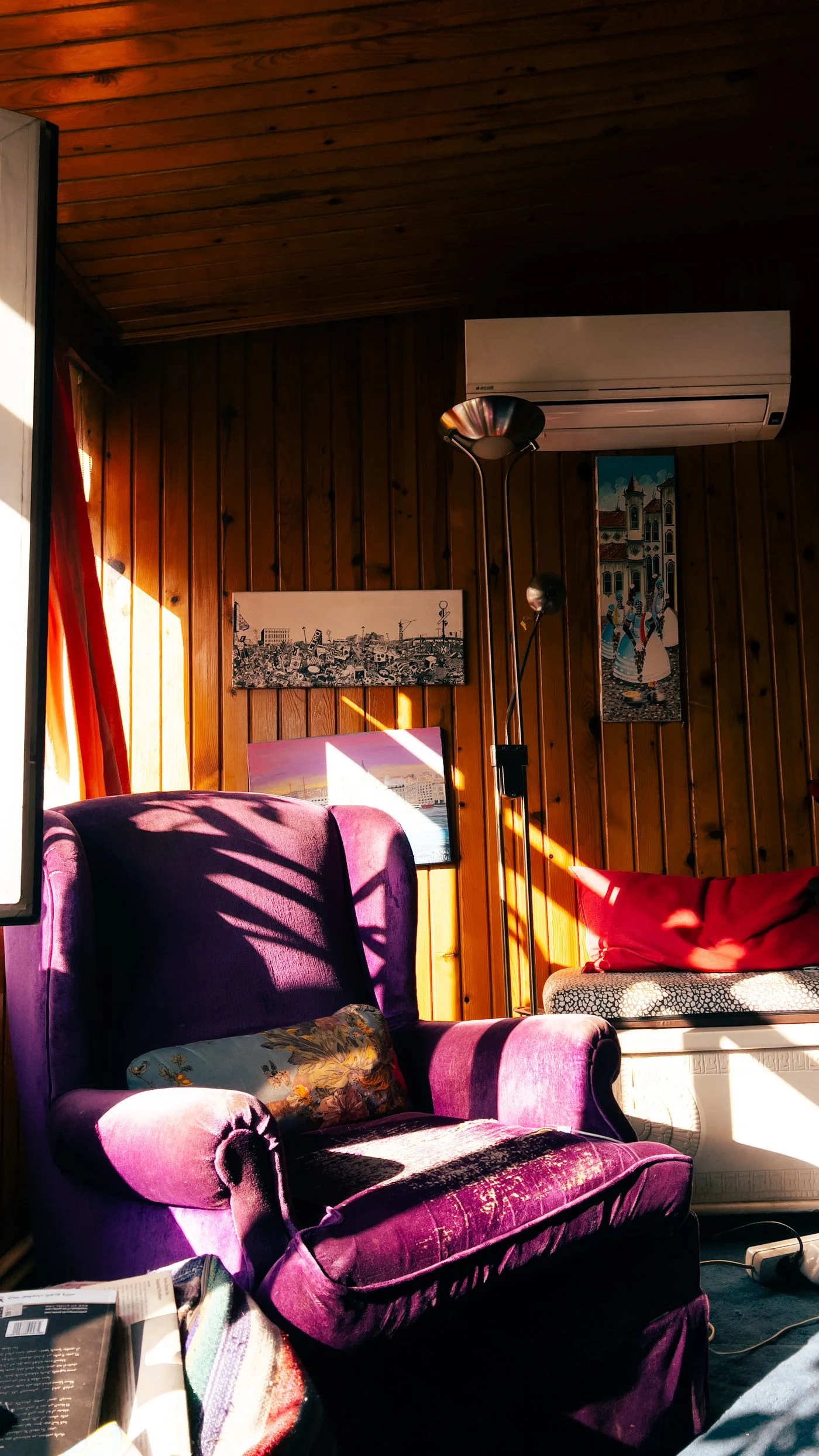 A purple upholstered chair in a sunlit room with wood-toned walls