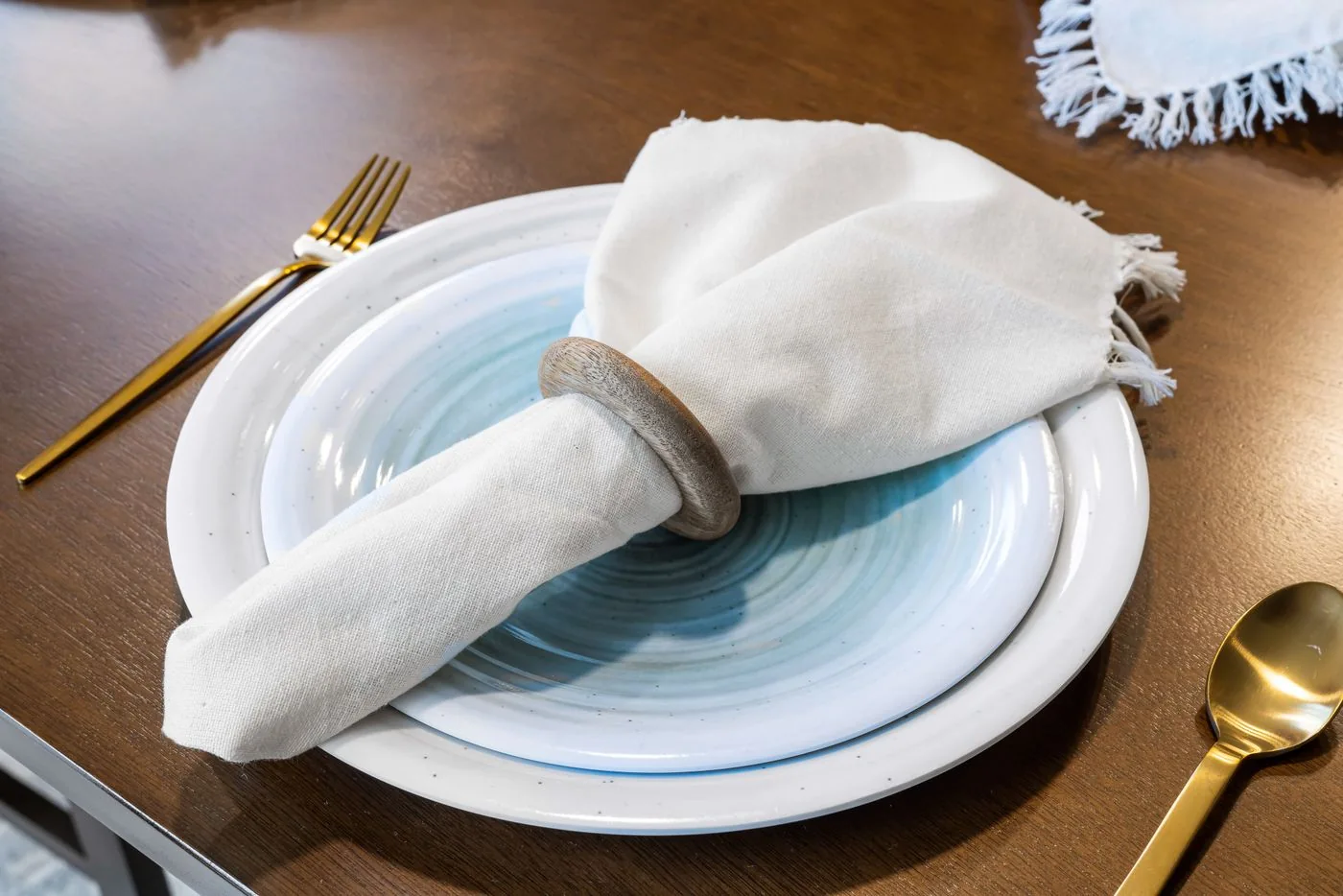 Pale plates, a light napkin and gold-toned cutlery on a table