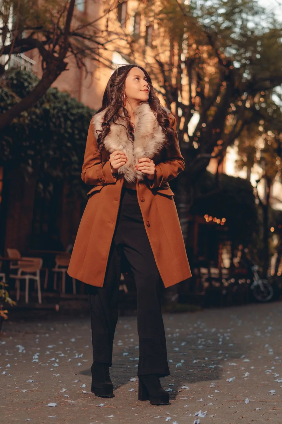 Woman in a brown coat standing on an autumn street