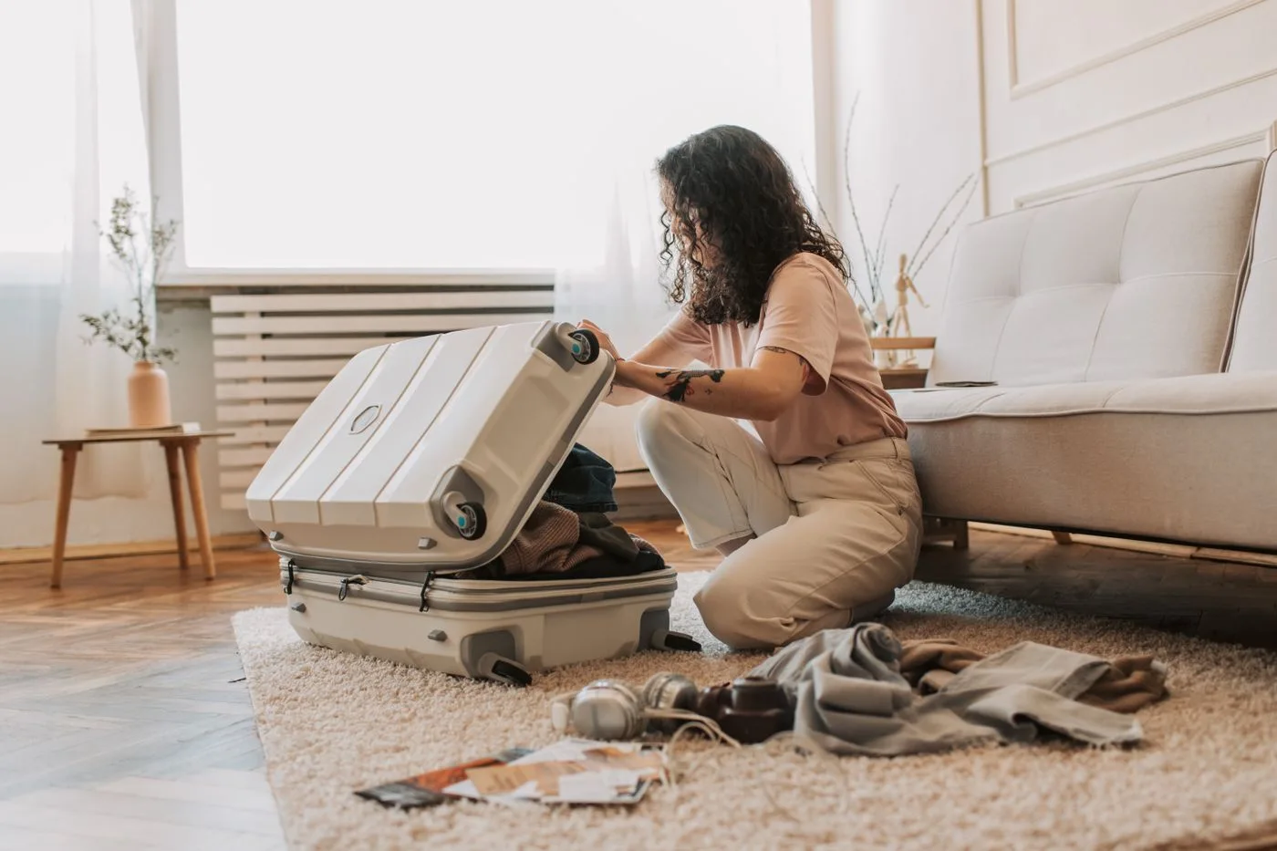 A woman packing an open suitcase in a living room