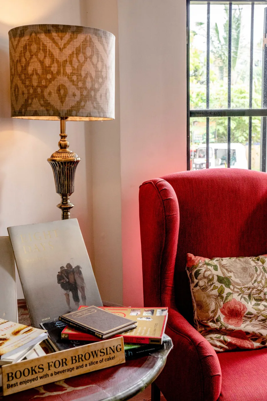 A red upholstered chair beside a tall decorative lamp