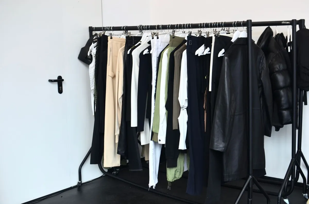 A clothing rack with mixed garments hanging in a bright room.