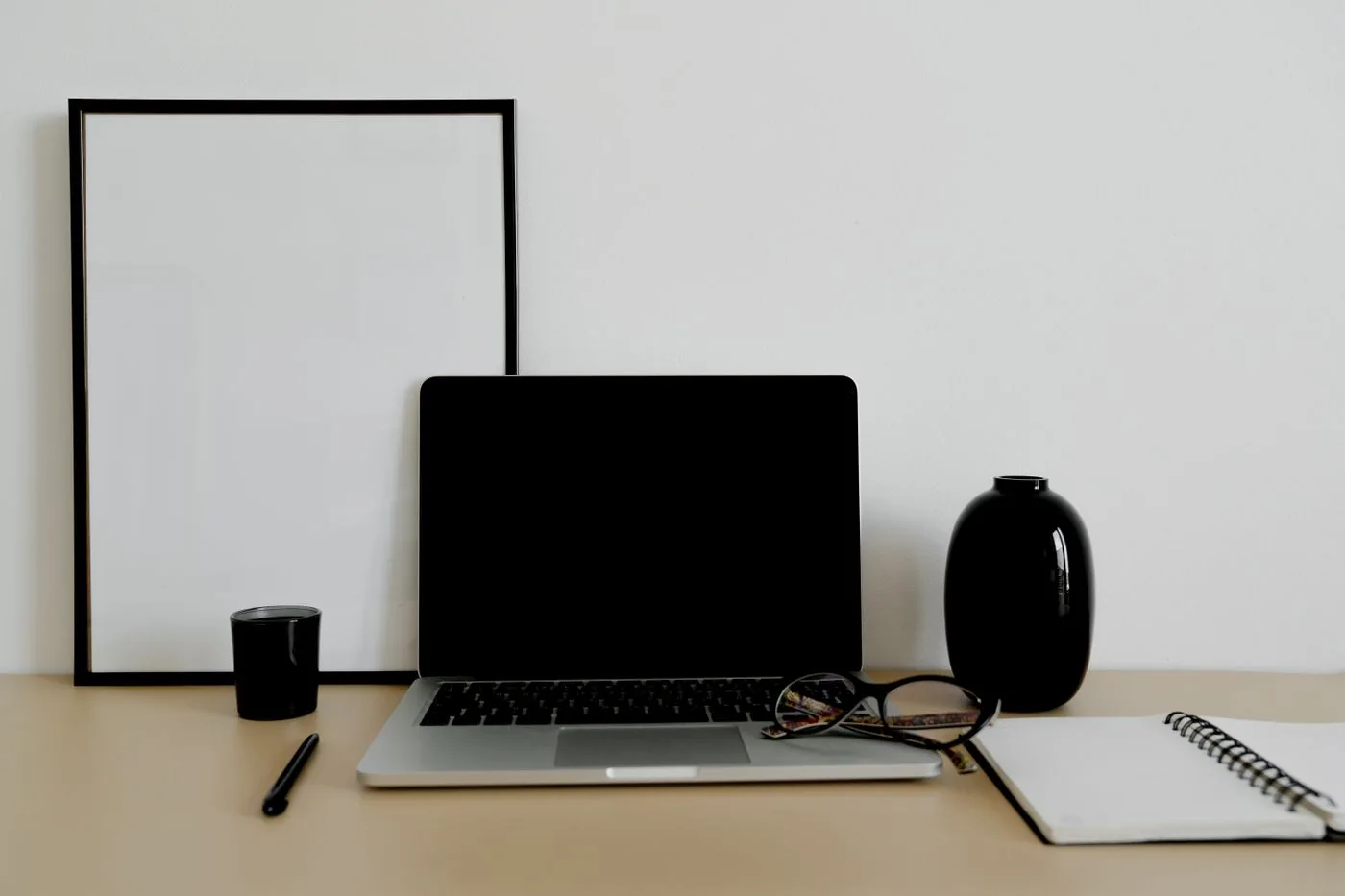 A desk with computer monitor, keyboard, framed print and headphones