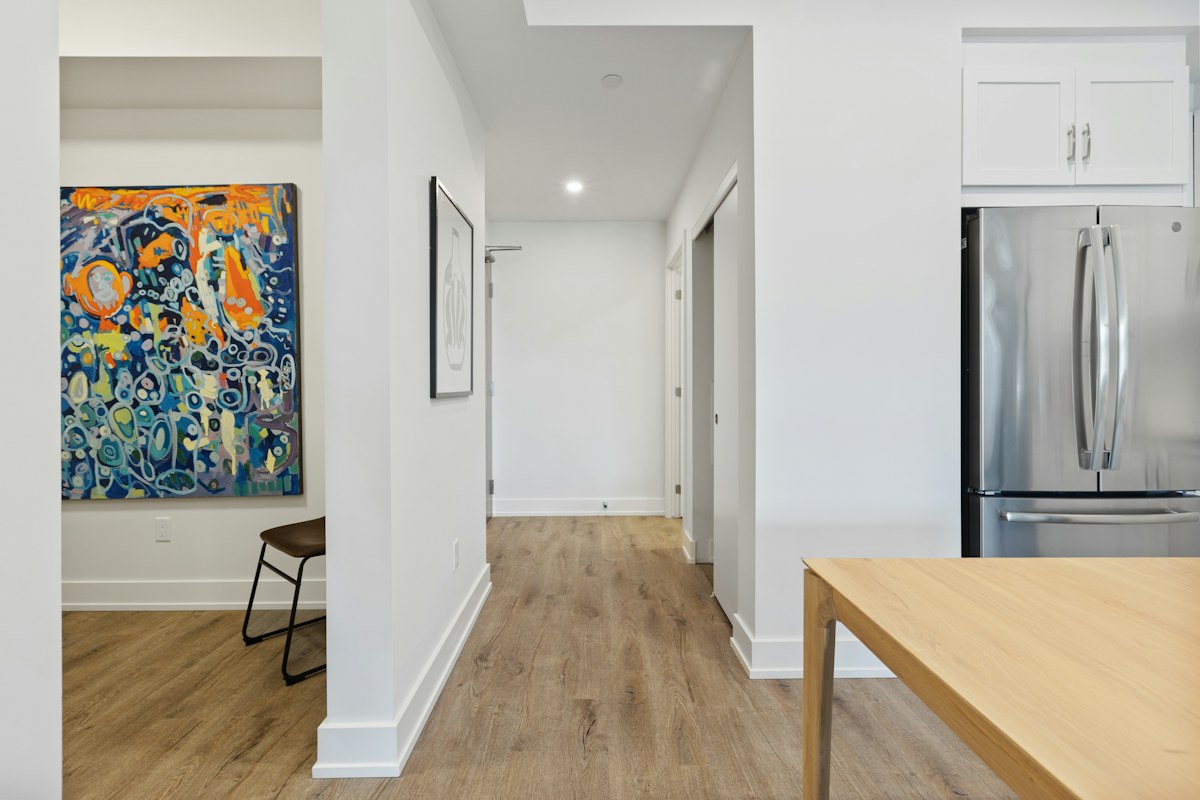 A pale kitchen with a wooden island, refrigerator and framed artwork
