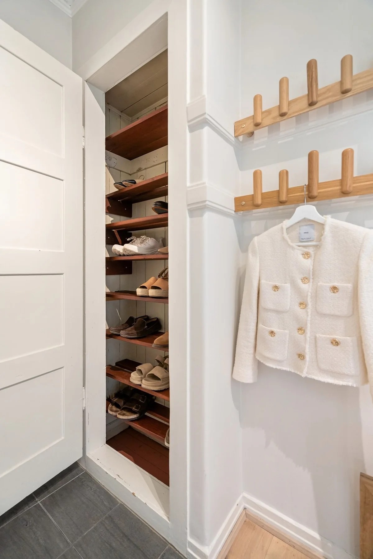 Open wardrobe with hanging clothes and shoes arranged on shelves.