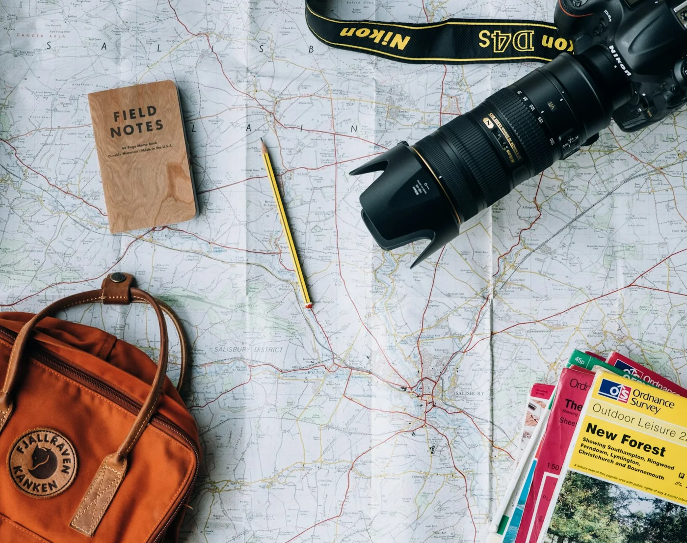 A leather bag, camera and travel items arranged on a map